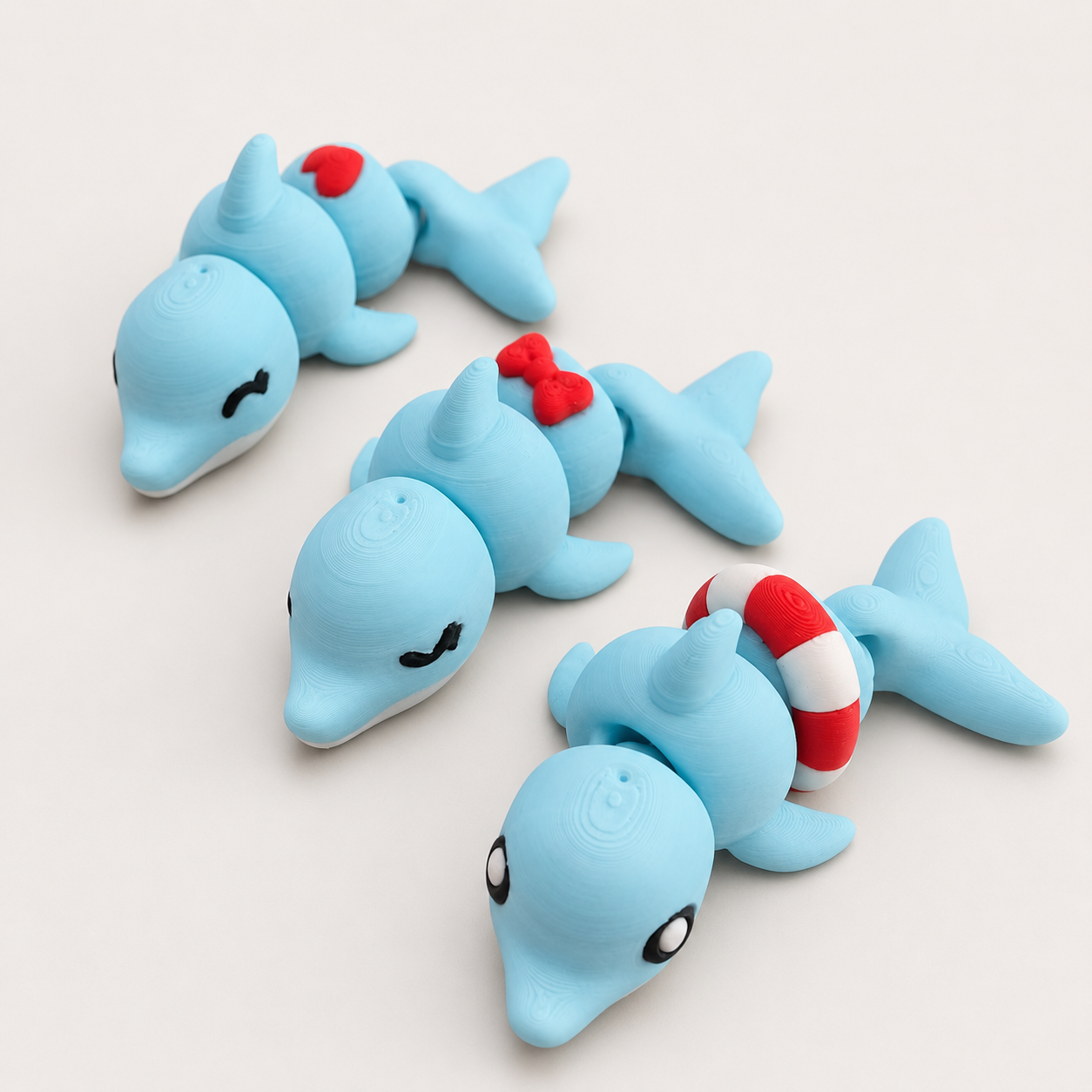 Mina, Lina und Nina – 3er-Set beweglicher Delfin-Figuren auf hellgrauem Hintergrund