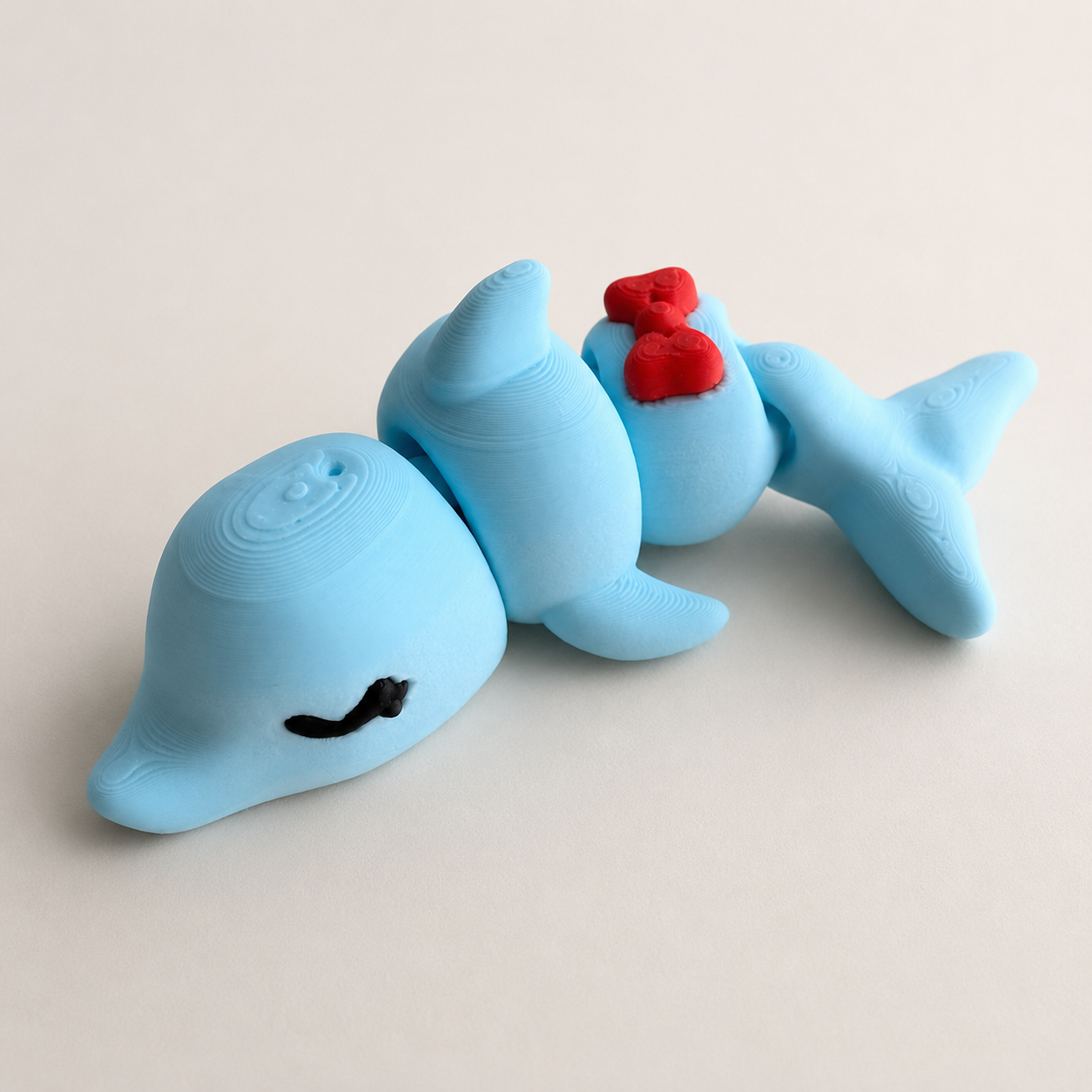 Lina der Delfin – Detailansicht mit roter Schleife, Gelenken und sichtbarer 3D-Druckstruktur